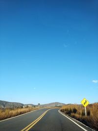 Country road against clear blue sky