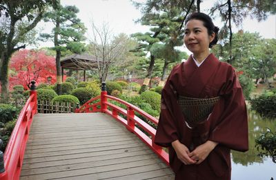 Smiling woman looking away while standing in park