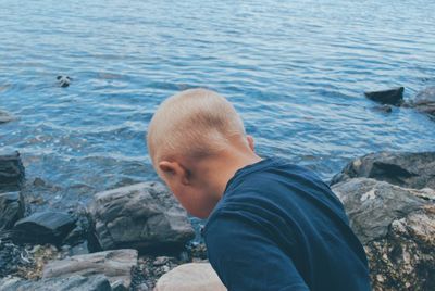 High angle view of boy on rock by sea