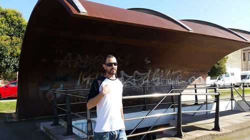 Portrait of smiling young man standing against built structure