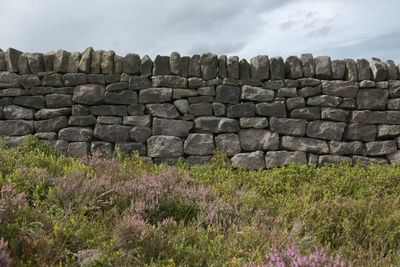 View of stone wall on field against sky
