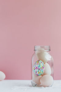 Close-up of eggs in jar on table against pink background