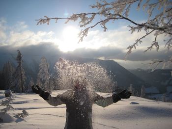 Woman standing on snow covered landscape against sky