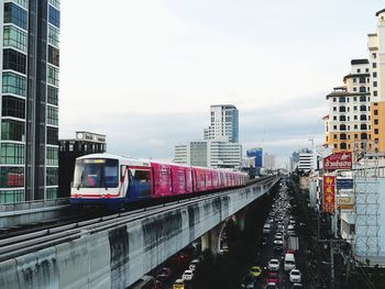 Train on bridge in city against sky