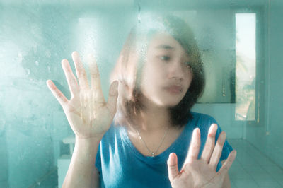 Close-up of woman with hand on window