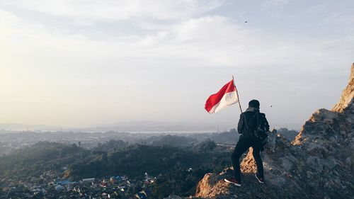 Rear view of man looking at cityscape against sky