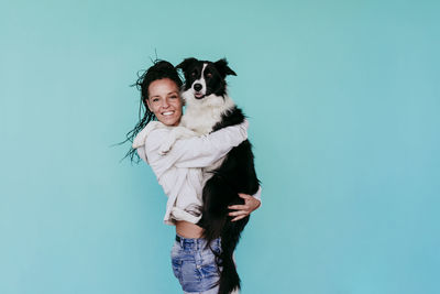 Portrait of smiling woman standing against blue background