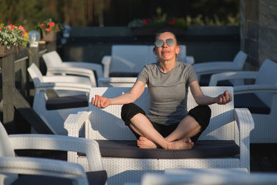 Mature woman meditating while sitting on sofa