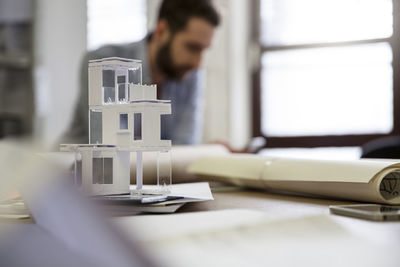 Desktop with architectural model and man in background