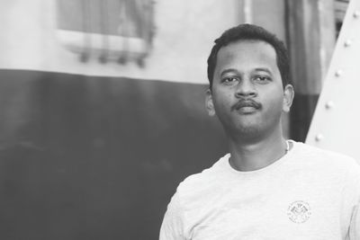 Portrait of young man standing against window