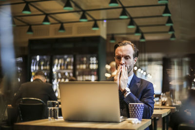 Worried businessman looking at laptop in restaurant