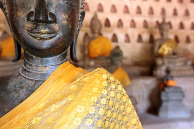 Cropped image of buddha statues against wall in temple