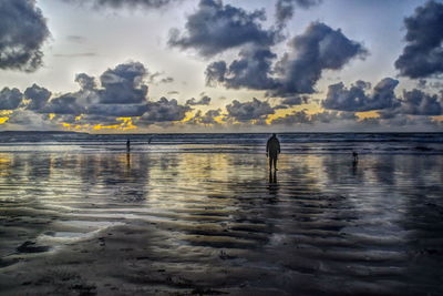 Silhouette man standing on beach against sky during sunset