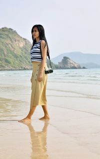 Full length of young woman standing on beach