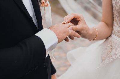 Midsection of bridegroom holding hands