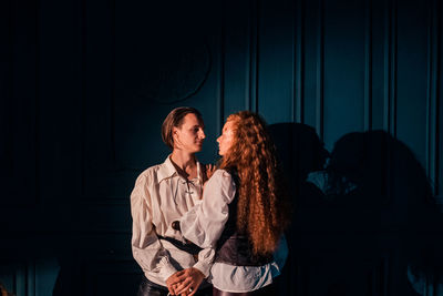 Young couple standing against wall