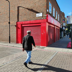 Rear view of man walking on footpath