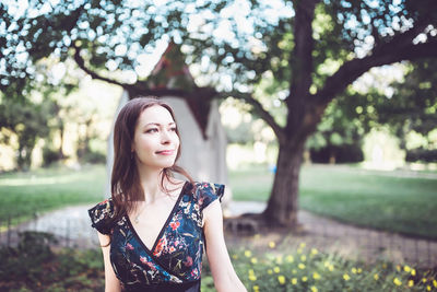 Cheerful optimistic brunette in a flower dress in the park