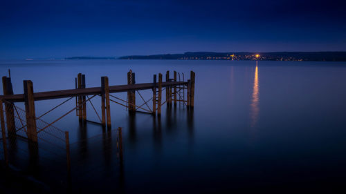 Pier on sea against sky at night