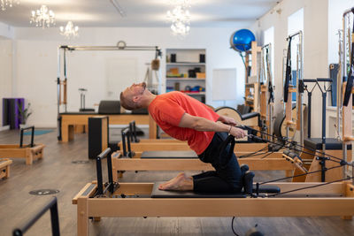 Male fitness pilates trainer shows exercises on special simulators. pilates stretch tables