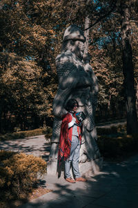 Statue of woman standing by tree in city