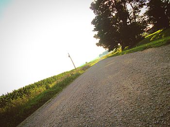 Road amidst field against clear sky