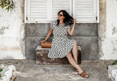 Portrait of young woman sitting on stone bench. summer, lifestyle, dress, fashion.