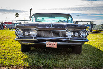 Old fashioned car on field against sky