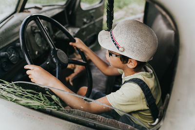 Boy holding steering wheel sitting in car