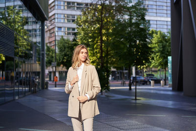 Portrait of young woman standing in city