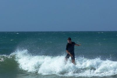 Man surfing against clear blue sky