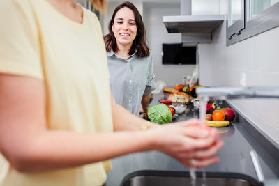 Midsection of woman washing apple at sink in kitchen
