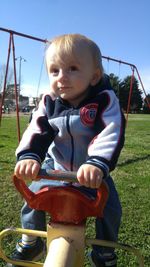 Portrait of boy sitting on slide at playground