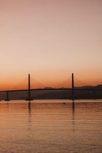 Suspension bridge over river against sky during sunset