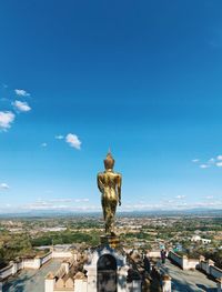 Statue against blue sky and buildings in city