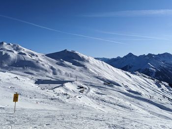 Scenic view of snow covered mountains against blue sky