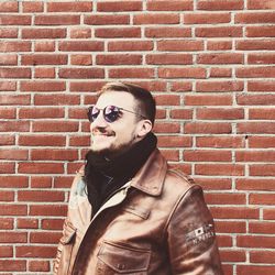 Portrait of man wearing sunglasses against brick wall