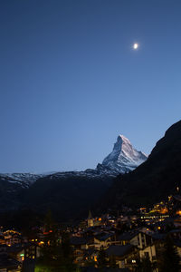 Illuminated buildings against clear sky at night