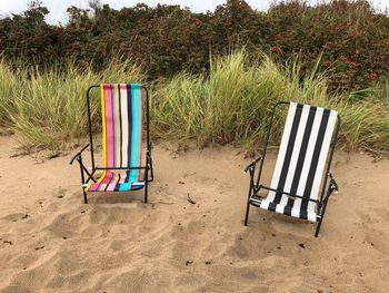 Empty chairs on sand at beach