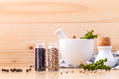 Beans in bottles with mortar and pestle on wooden table