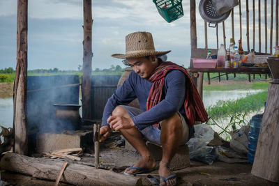  young man working with tool while sitting outdoors