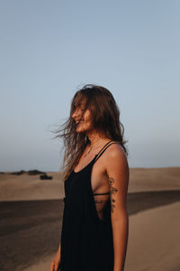 Beautiful woman standing in desert against sky