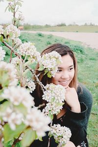 Thoughtful woman crouching by white flowers at park