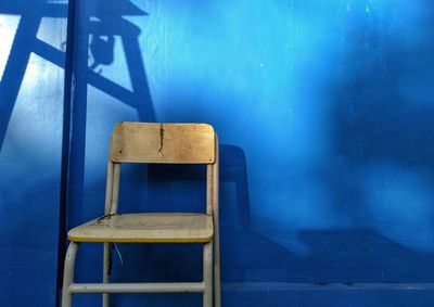 Close-up of empty chair against wall