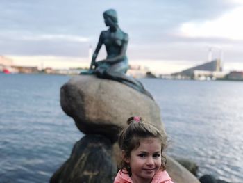 Portrait of boy on rock by sea against sky