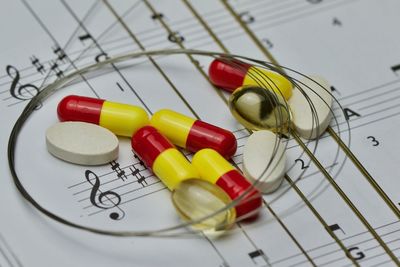 High angle view of drugs and string on sheet music