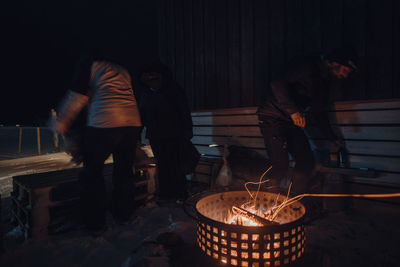Side view of man standing by campfire at night
