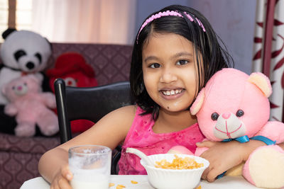 An indian girl child eating cereal with milk with smiling face and looking at camera