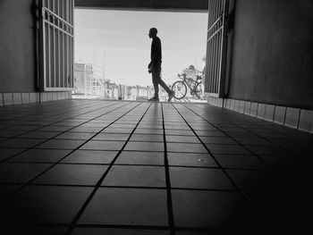 Rear view of man on bicycle amidst buildings in city