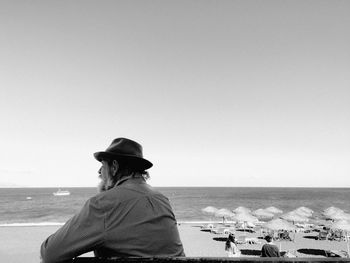 Rear view of man looking at sea against clear sky